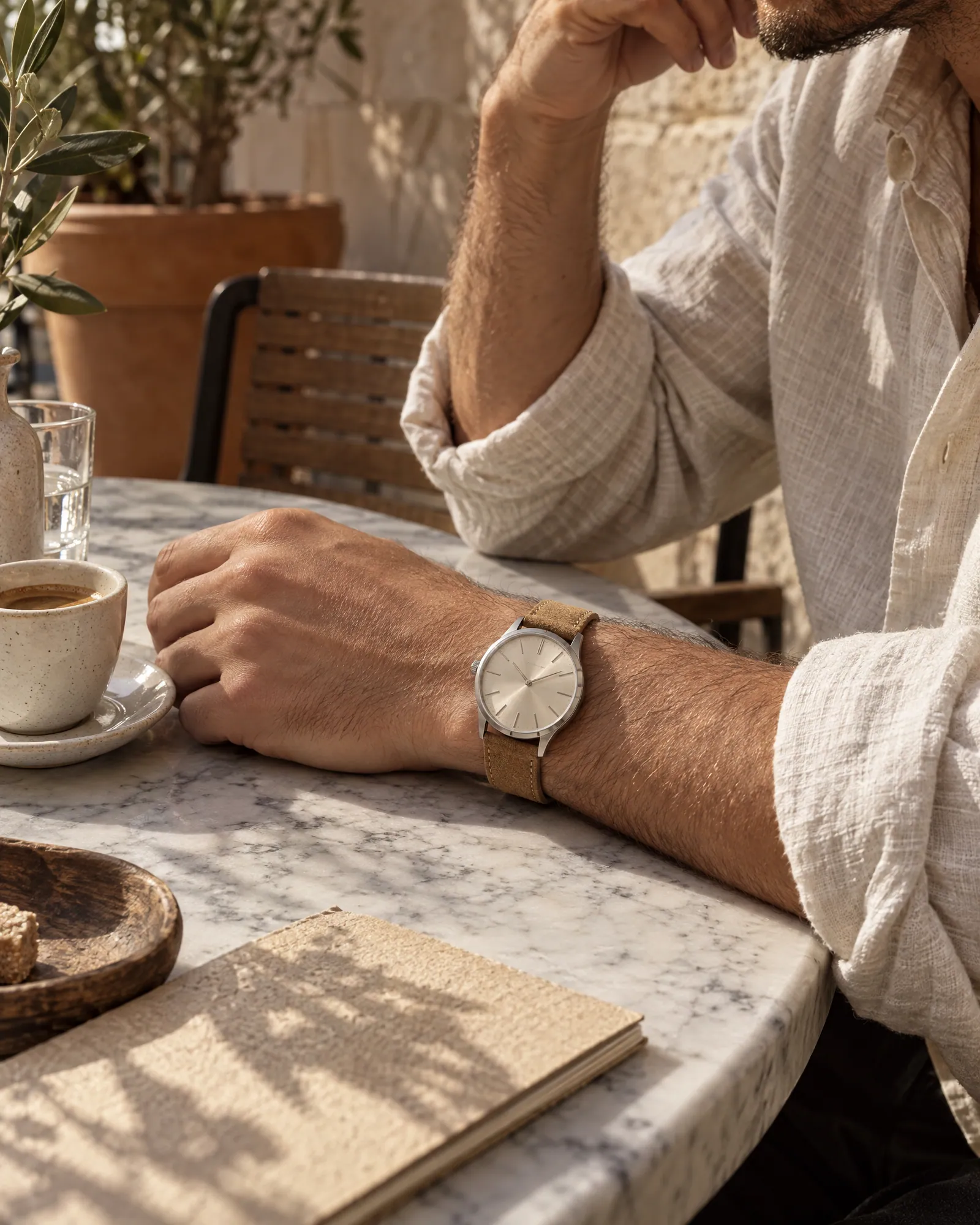 Cream-dial watch with tan strap worn at a cafe table (Helium-made example)